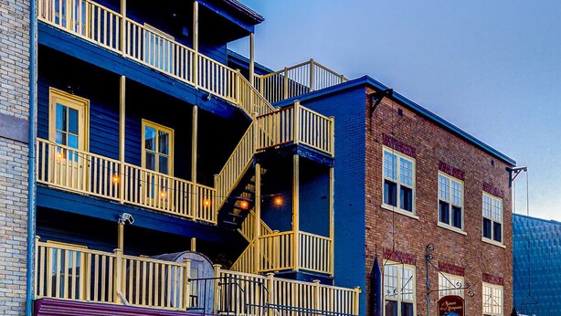 Un hotel de varios pisos con fachada azul, varios balcones y planta baja de ladrillo.
