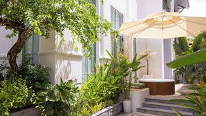 A courtyard with a hot tub, potted plants, and a large umbrella. - Fortune Villa Phu Quoc (An Thoi)