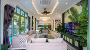 A spacious living area with a sofa, coffee table, and a TV on a stand. - Fortune Villa Phu Quoc (An Thoi)