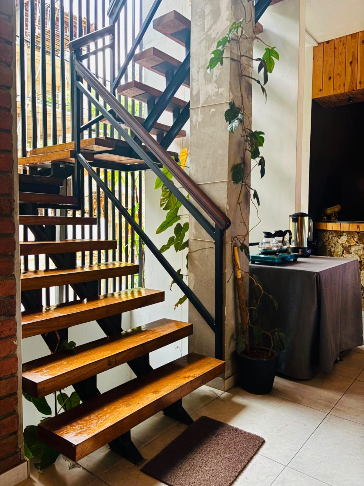 A staircase with wooden steps and black metal railings, a potted plant, and a table with a tablecloth.
