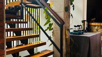 A staircase with wooden steps and black metal railings, a potted plant, and a table with a tablecloth.