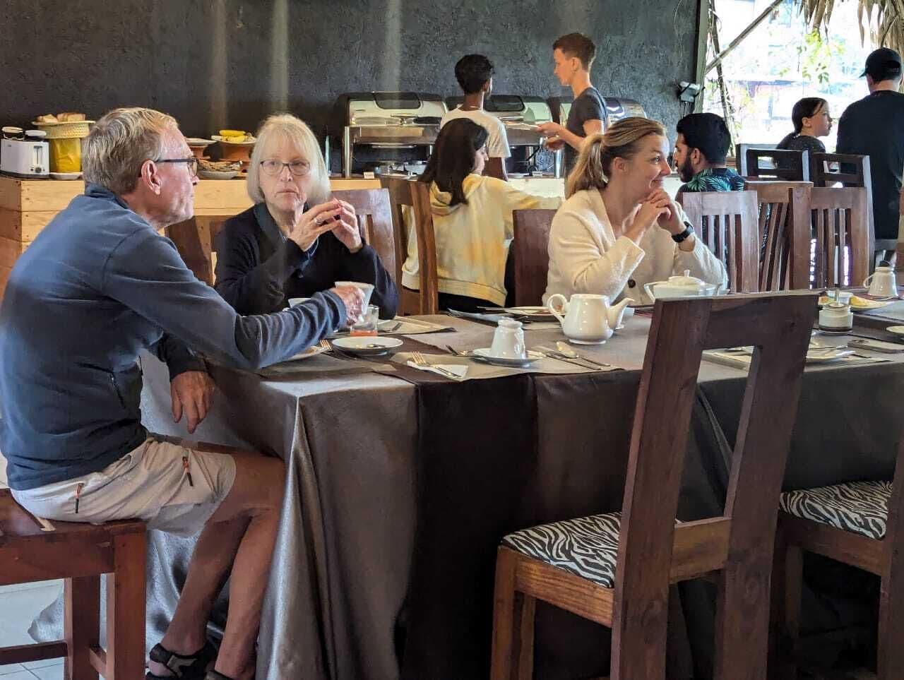 Ein Essbereich mit Holztischen und -stühlen, einer Kaffeemaschine und einer Speiseauslage im Hintergrund.