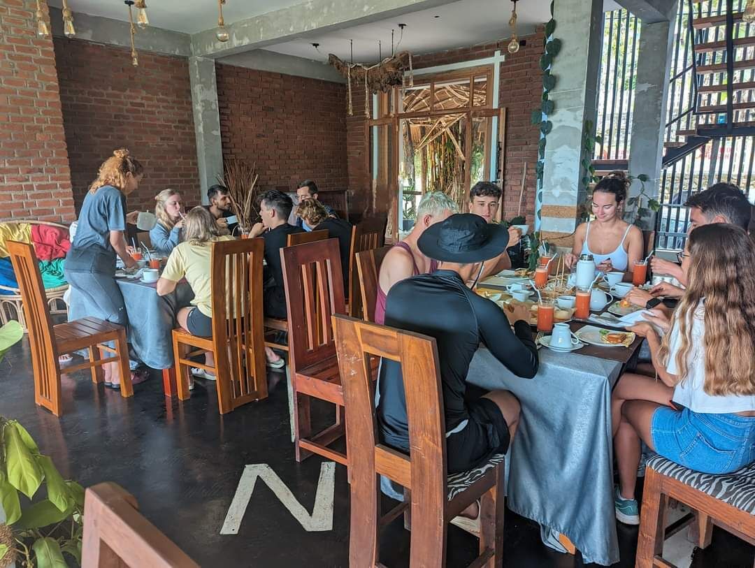 A restaurant with wooden chairs and tables, brick walls, and hanging lights.