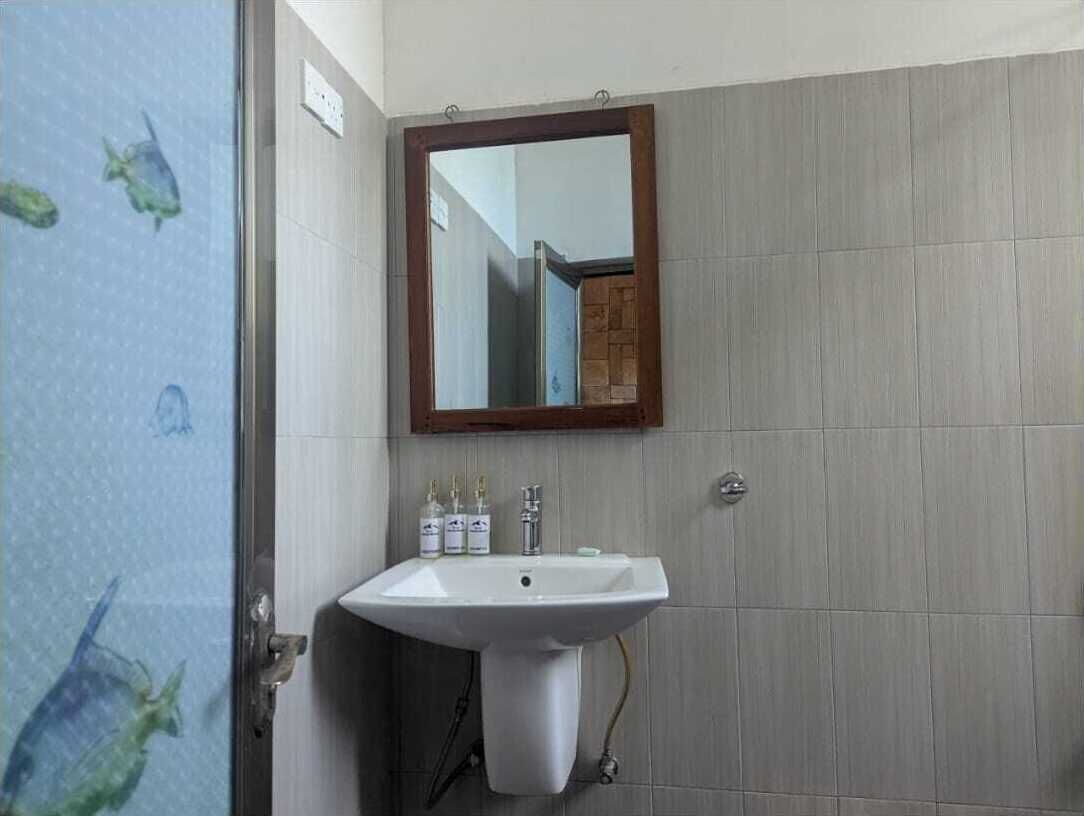 A bathroom with a white sink, a mirror, and tiled walls.