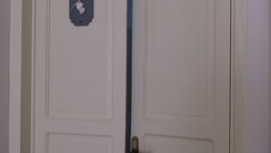 A closed door with a keyhole and a small decorative plate. - The White Room Courtyard (Scicli)