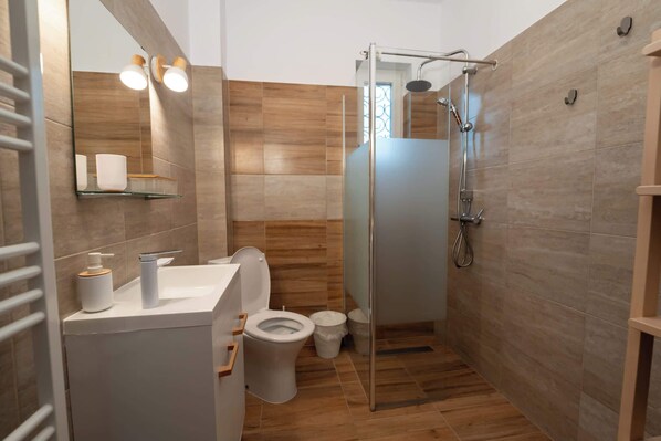 Une salle de bain moderne avec une douche à parois de verre, des toilettes et un lavabo avec un miroir au-dessus.