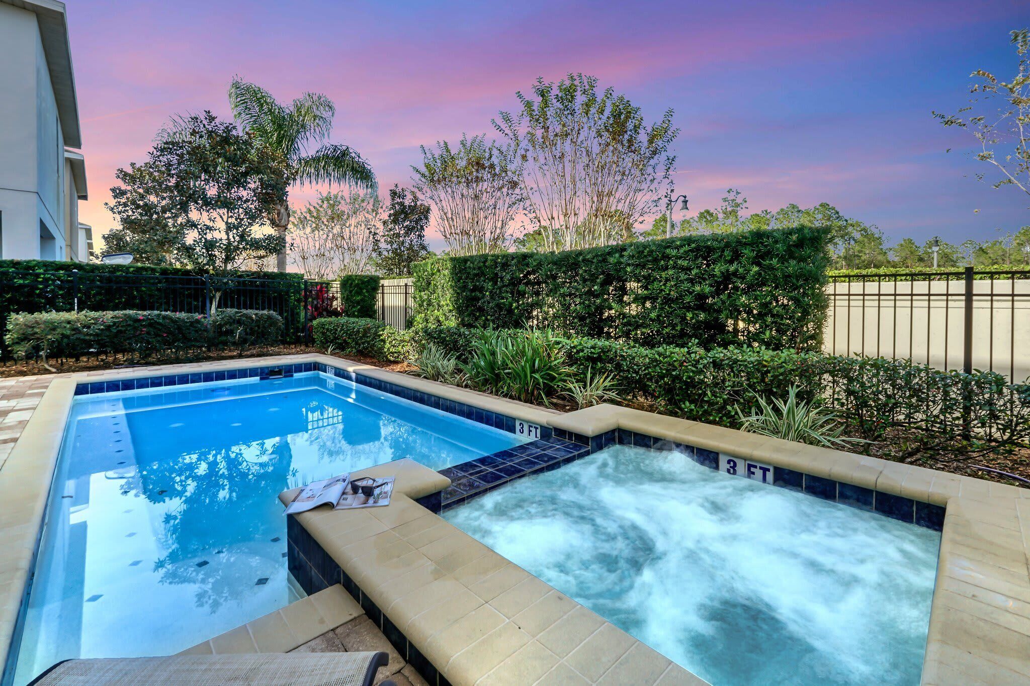 Relax in the private pool and hot tub area surrounded by lush greenery at sunset.