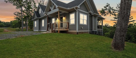 A two-story house with a covered porch, large windows, and a well-maintained lawn.