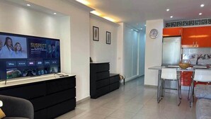 Een moderne woonkamer met een flatscreen televisie, een zwarte entertainmentkast en een grijze bank.