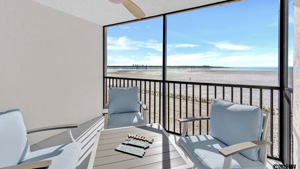Ein Balkon mit Blick auf den Strand, einem Deckenventilator und zwei Stühlen.