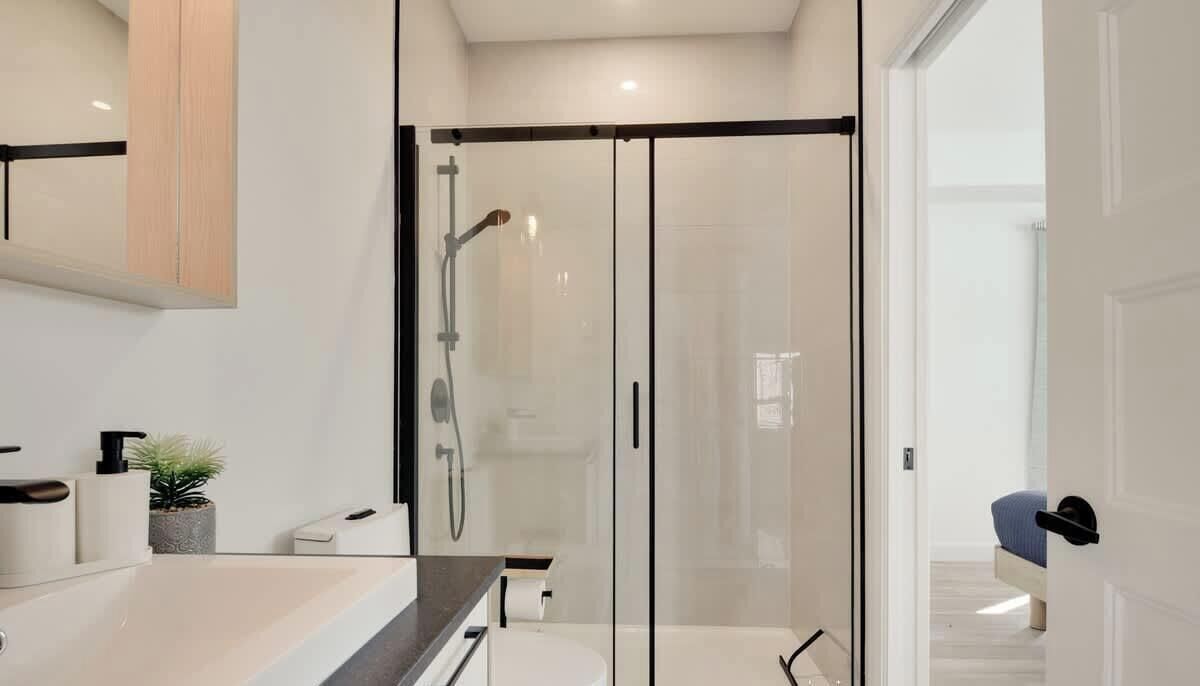 Un bagno moderno con cabina doccia in vetro, un water e un lavabo con piano.