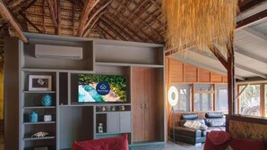 Een moderne woonkamer met een televisie, houten meubels en uitzicht op het groen.
