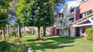 A courtyard with a lawn, trees, and a building with balconies. - Islantilla Golf Holiday Home with Private Terrace, Wi-Fi, and Air Conditioning (Huelva)
