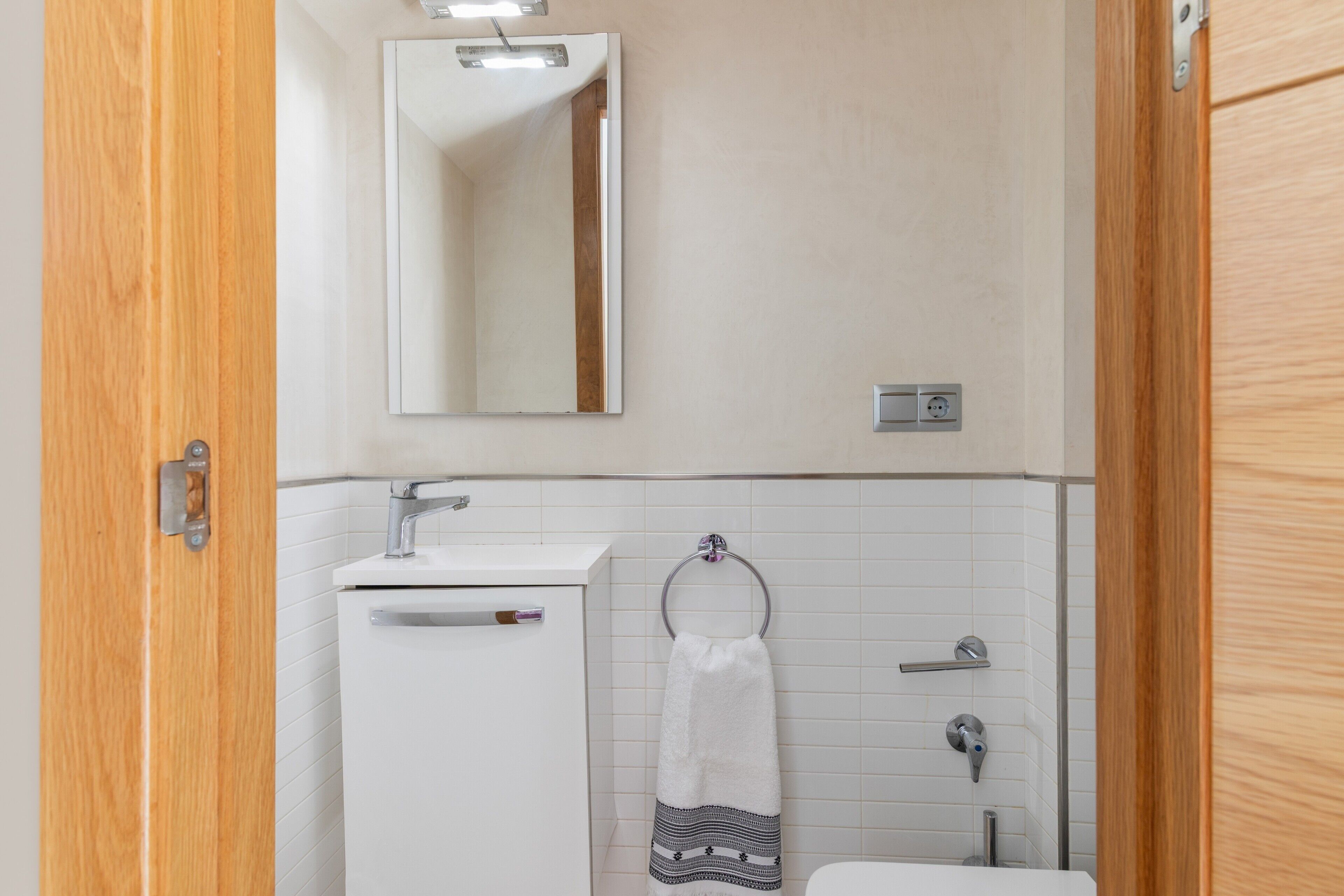 A bathroom with a white sink, a mirror, a towel rack, and a toilet.