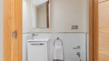 A bathroom with a white sink, a mirror, a towel rack, and a toilet.