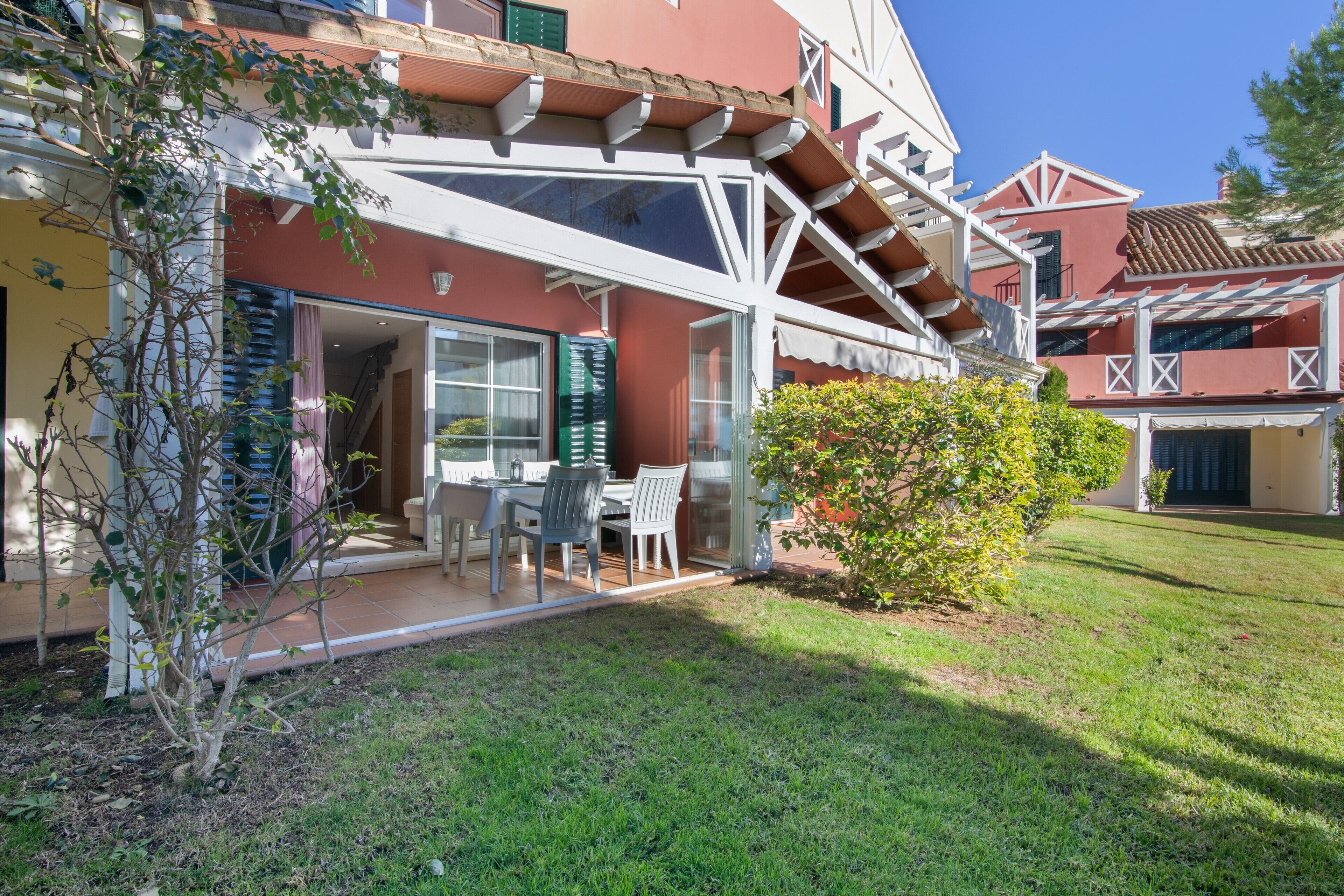 Un edificio residencial con patio, zona de comedor y pequeño jardín.