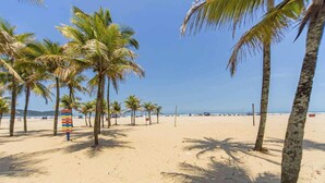 A beach with palm trees and a volleyball net. - Apartamento na Praia Grande com vista mar (Praia Grande)