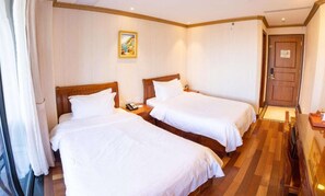 Ein Hotelzimmer mit zwei Betten, einem Holz-Kopfteil, einem Bild an der Wand und einer Tür mit einem Schild.