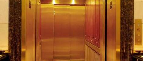 An elevator with a marble floor and a golden frame.