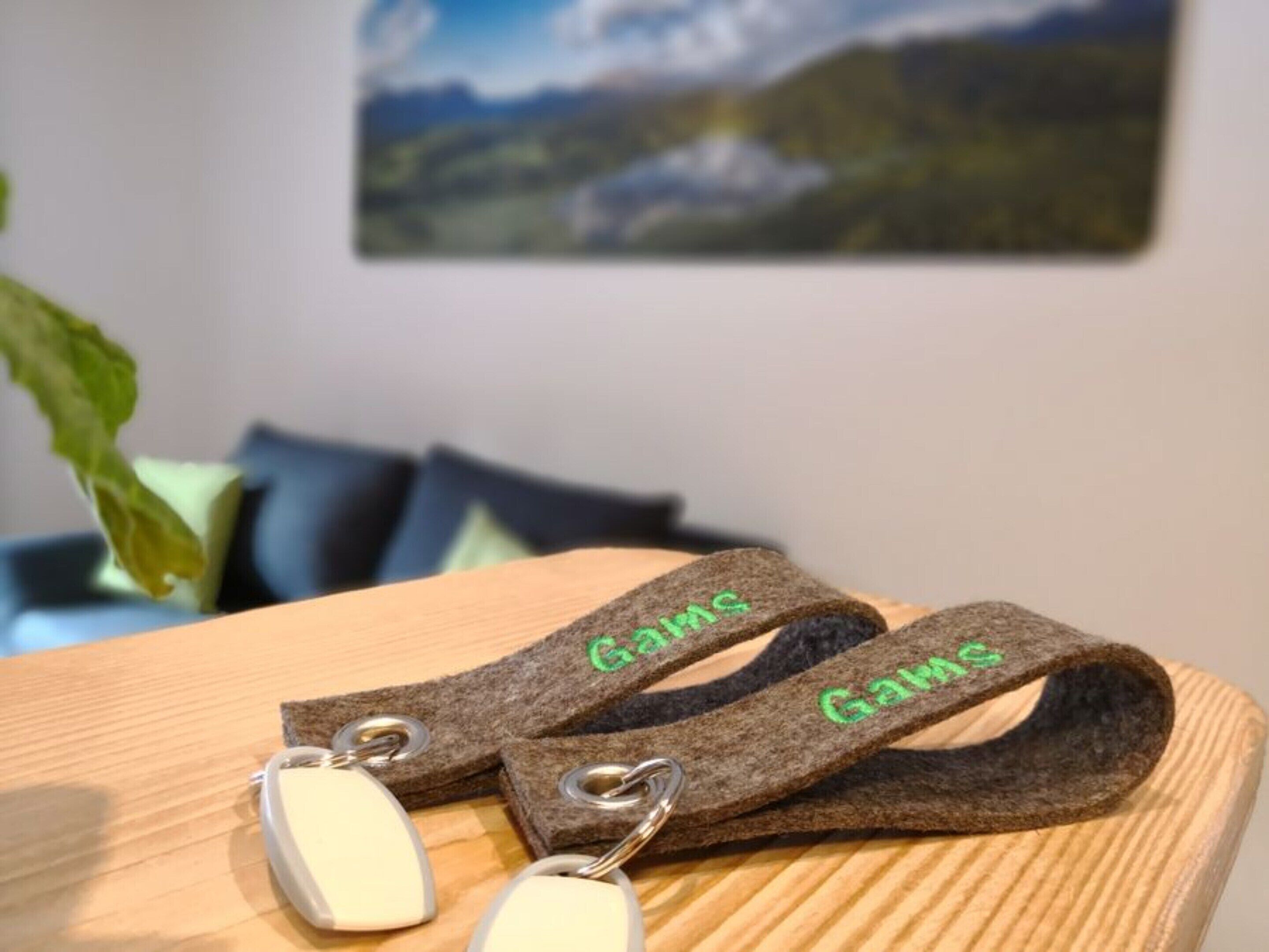 A pair of keychains with the word "Gams" on a wooden surface.