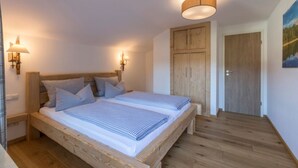 A bedroom with a wooden bed, two bedside tables, a wooden wardrobe, and a painting on the wall. - Apartment in Grainau am Badersee (Grainau)