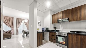 Une cuisine moderne avec des meubles en bois, un four encastré et un coin repas comprenant une table et des chaises.