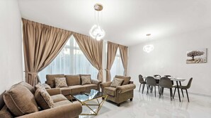 Un salon moderne avec des canapés de couleur beige, une table basse en verre et un coin repas comprenant une table et des chaises.