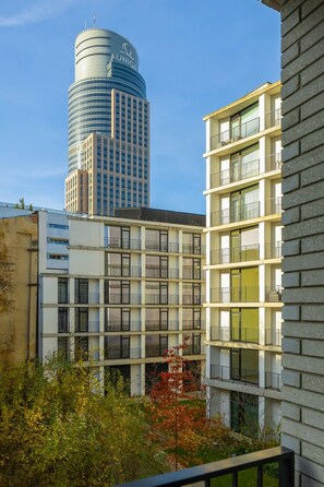 Ein modernes Gebäude mit mehreren Balkonen und einem zylindrischen Turm im Hintergrund.