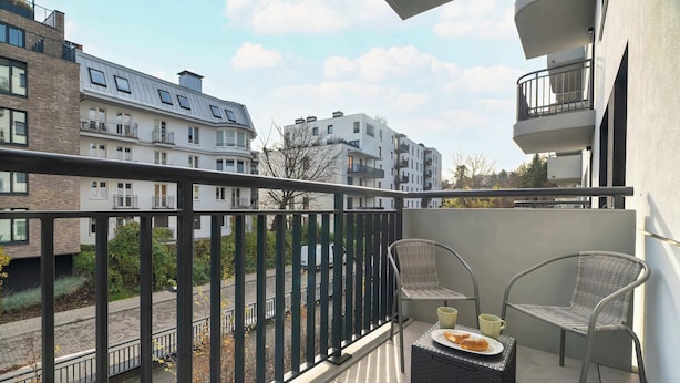 A balcony with two wicker chairs, a small table, and a plate of food. - Modern Apartment | Private Parking and Balcony (Poznań)