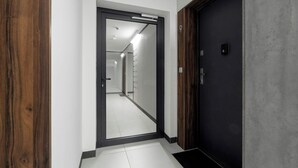 A hallway with a mirrored door leading to a bright, tiled corridor. - Modern Apartment | Private Parking and Balcony (Poznań)