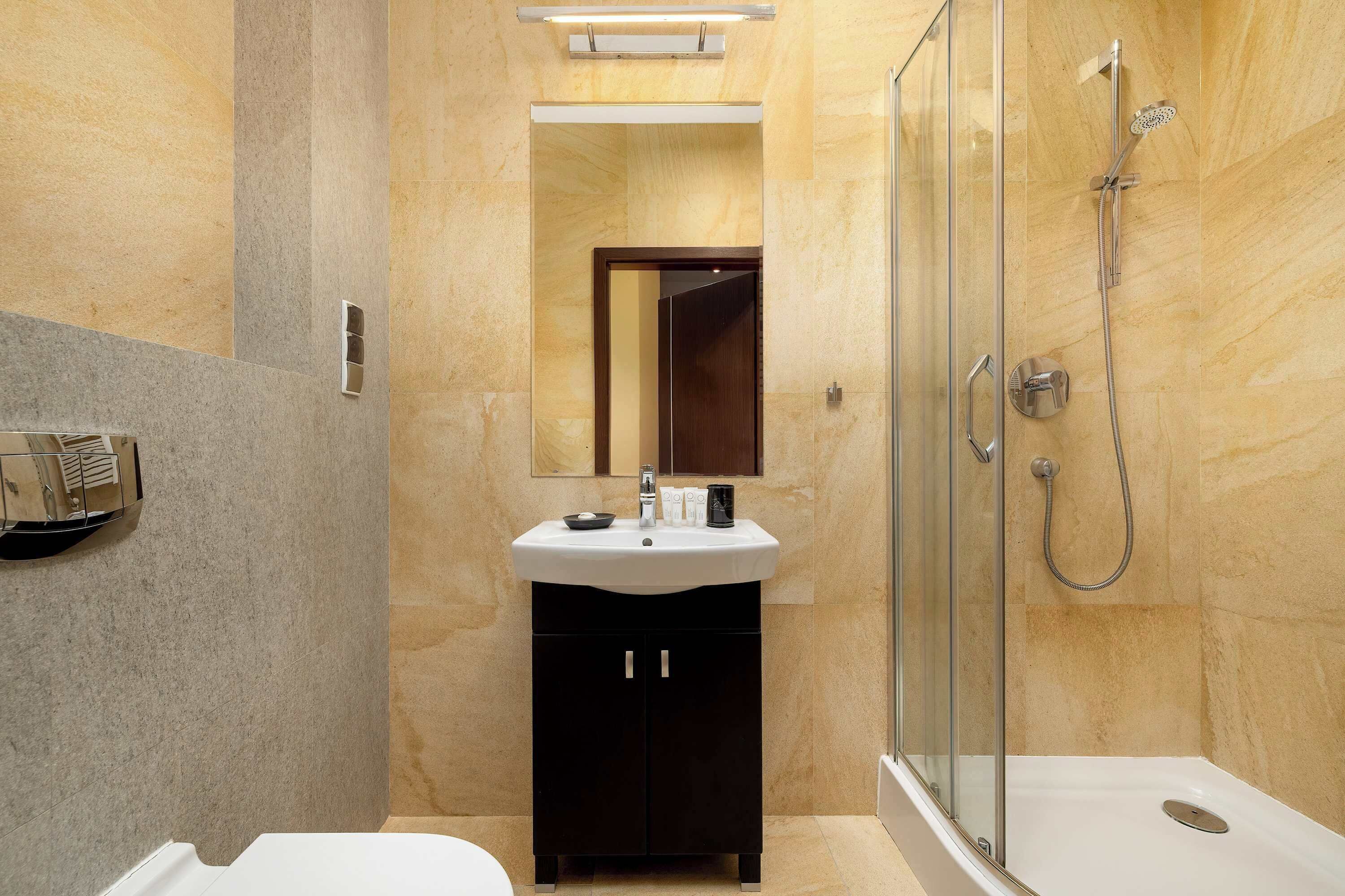 Een moderne badkamer met een douchecabine van glas, een wit wastafelmeubel en donkere kastjes.