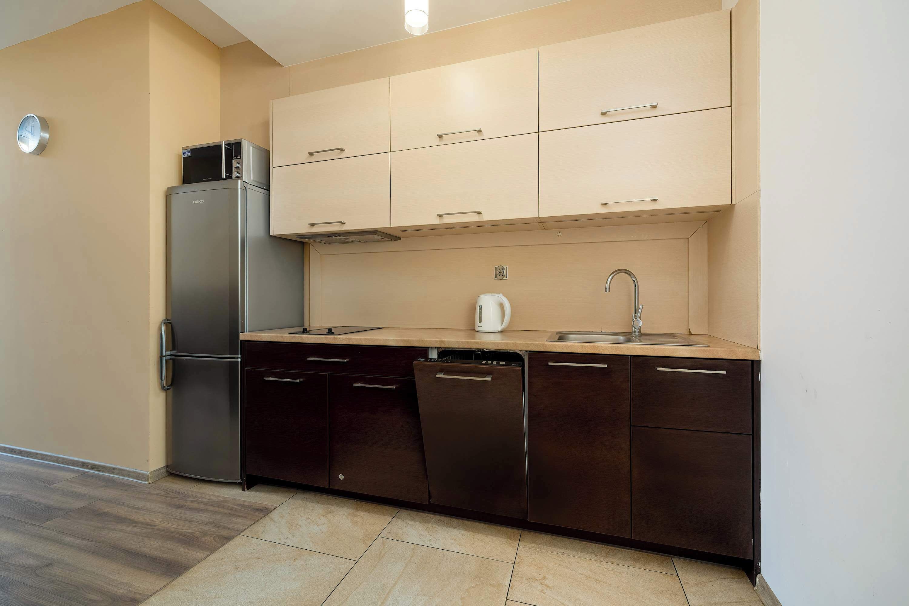 A compact kitchen with a refrigerator, dishwasher, and a coffee maker on the countertop.