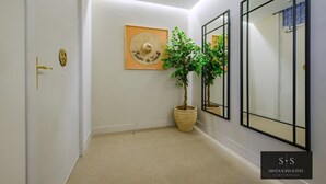 Ein Flur mit einem Blumentopf, einem gerahmten Kunstwerk und einer Tür mit goldener Griff.