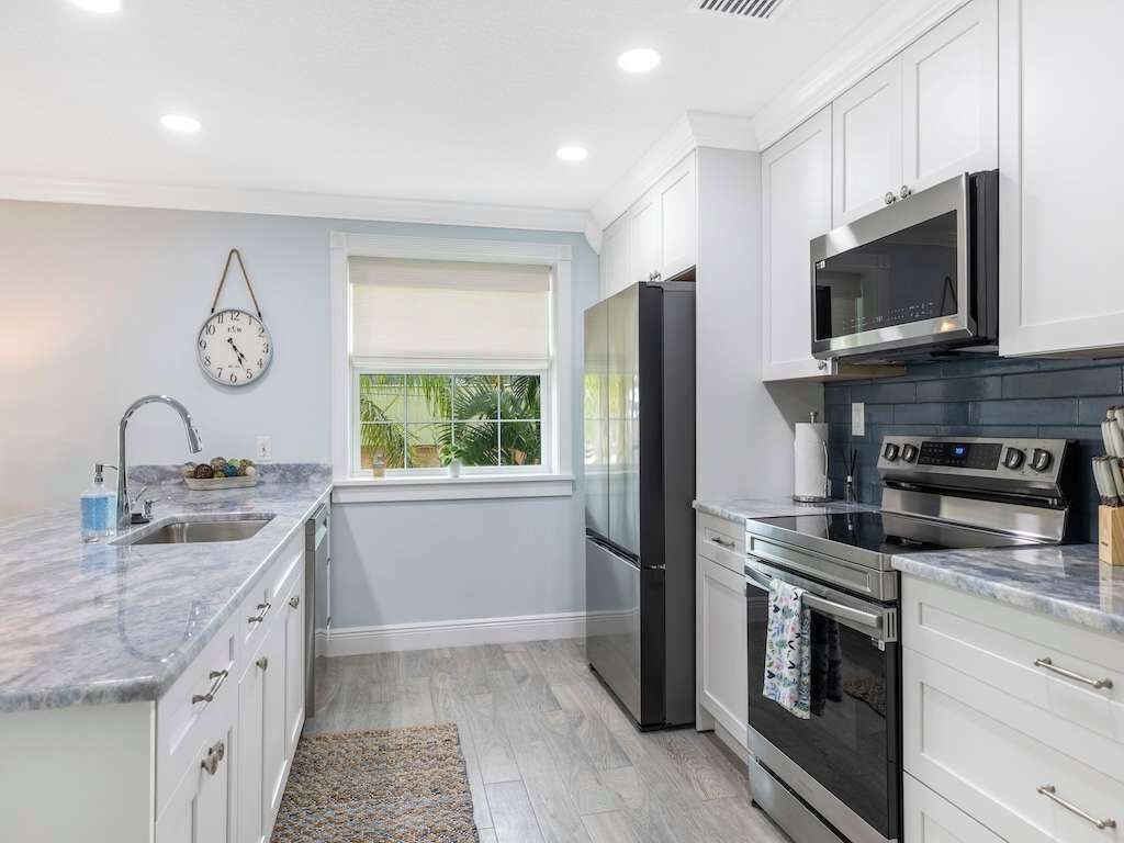A modern kitchen with white cabinets, a stainless steel refrigerator, a microwave, and an oven.