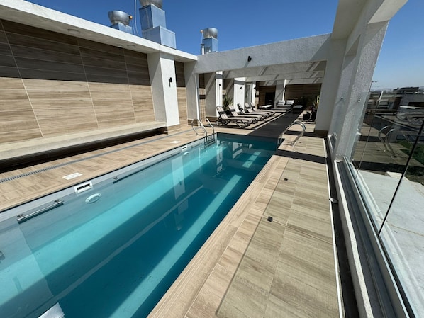 Una piscina en terrat amb vistes clares al perfil urbà de la ciutat, seients relaxants i un disseny arquitectònic modern.