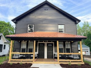 A two-story building with a porch, a black door, and a small window. - #2 Richards Ave Cozy Brand New 1BR apt half mile CASV (Oneonta)