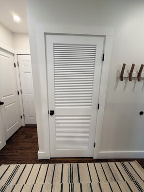 A hallway with white doors, a patterned rug, and a wall-mounted coat rack. - #2 Richards Ave Cozy Brand New 1BR apt half mile CASV (Oneonta)