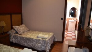 A hotel room with a bed, a desk, and a bathroom visible through an open door. - HOSTAL PENSION LA RUTA (Escacena del Campo)