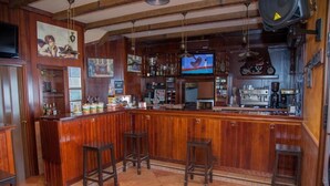 Eine Barbereich mit Holzhockern, einem Fernseher und diversen Barutensilien.