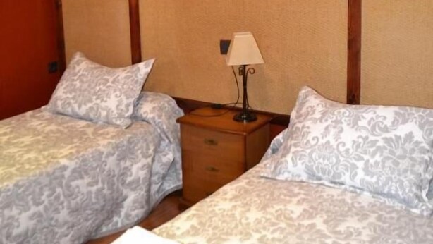 Ein Hotelzimmer mit zwei Betten, einem Nachttisch mit Lampe und einer Klimaanlage an der Wand.
