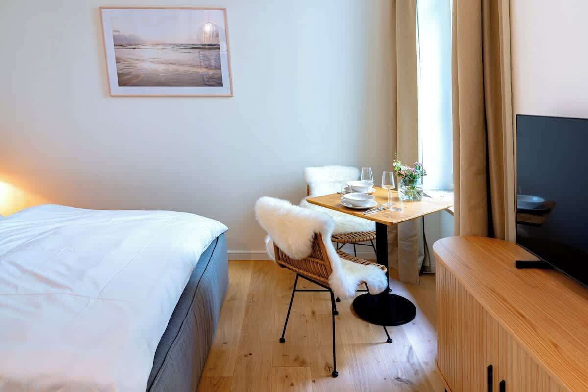 Ein Hotelzimmer mit einem Bett, einem Esstisch mit Stühlen, einem Fernseher und einem Bild an der Wand.