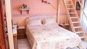 Une chambre à coucher avec un lit, des tables de chevet, une commode, une échelle et une étagère ornée de fleurs.