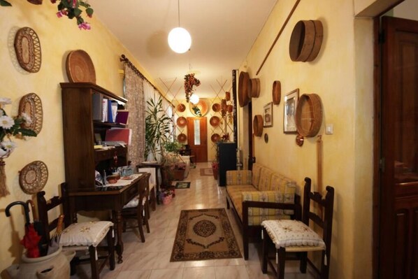 A cozy living room with a sofa, chairs, a coffee table, and a dining area with a table and chairs. There are decorative items like vases and a plant on the walls. - Beb "Ziu Antoi and Aunt Srivia" (Sestu)