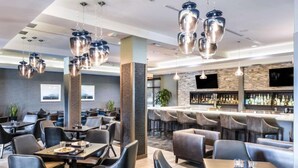 A modern restaurant with high chairs, tables, and hanging pendant lights. - Prime Milpitas Location | Pool, Fitness & Dining (Milpitas)