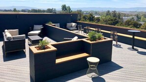 A rooftop terrace with built-in seating, a small table, and planters. - Prime Milpitas Location | Pool, Fitness & Dining (Milpitas)