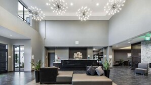 Et hotel lobby med reception, siddeområde og moderne lysarmaturer.