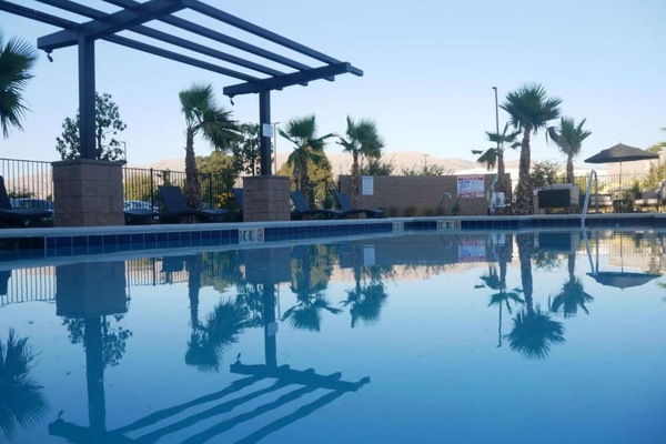 Peaceful pool with palm trees and lounge chairs by the mountain view