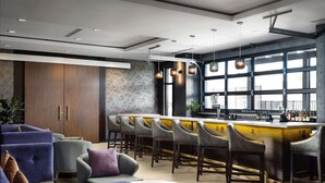 Un espace bar moderne doté d’un comptoir, de sièges et de grandes fenêtres.