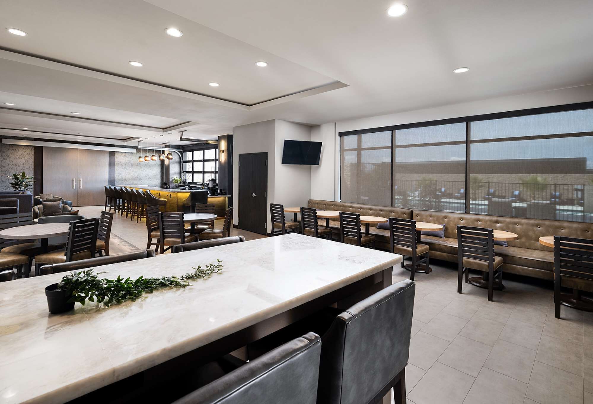 Een moderne hotel lobby met een marmeren receptiebalie, zithoeken en grote ramen met uitzicht op de stad.