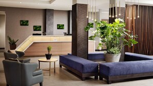 Un hall d’entrée moderne avec un comptoir d’accueil, un espace salon et des plantes en pot.